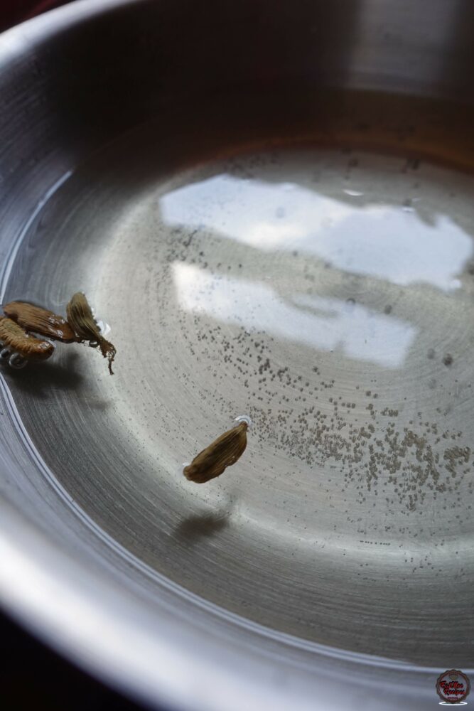 Once the sugar has dissolved, add in the cardamom (elachi) pods, turn up the heat & allow it to come to a boil.