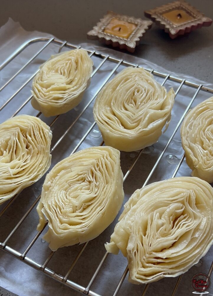 After the puri's have been soaked, place them all onto a wire rack. Add some parchment paper below it to catch excess syrup.