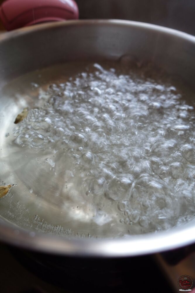 Once the sugar has dissolved, add in the cardamom (elachi) pods, turn up the heat & allow it to come to a boil.